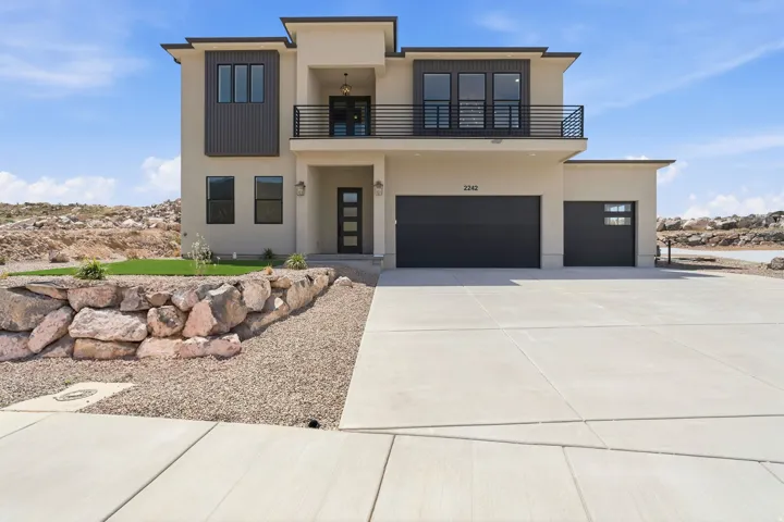 Contemporary stucco exterior featuring a second-story balcony with black metal railing, a two-car garage, a single-car garage, and a concrete driveway