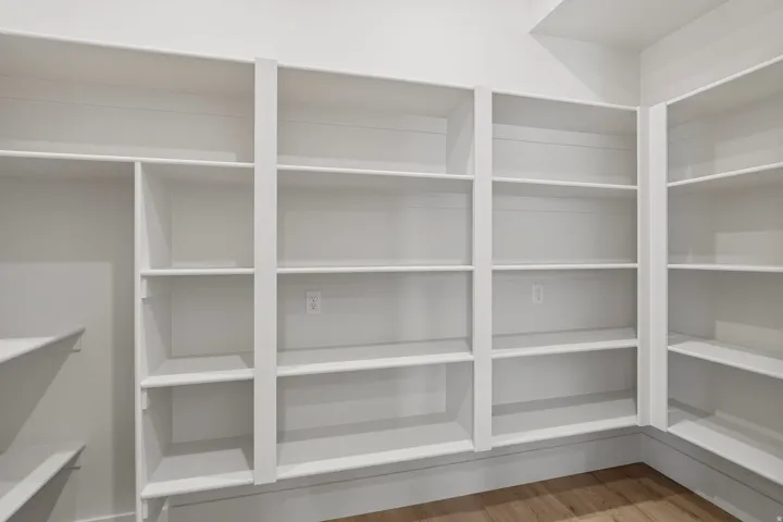 White built-in shelving system featuring multiple tiers, corner storage, and integrated electrical outlets