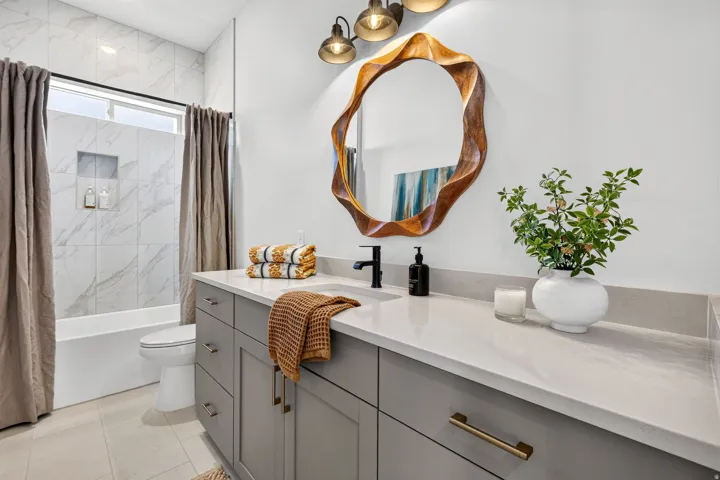 Contemporary bathroom featuring a spacious vanity with a light-colored countertop, an undermount sink, and matte black fixtures