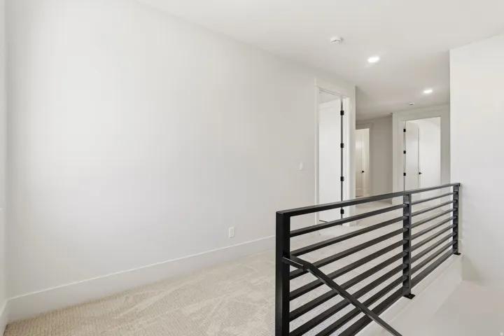 Carpeted upper-level landing featuring a modern black horizontal bar railing