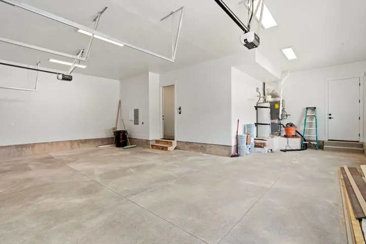 Spacious garage featuring a concrete floor, bright overhead lighting, and white painted walls
