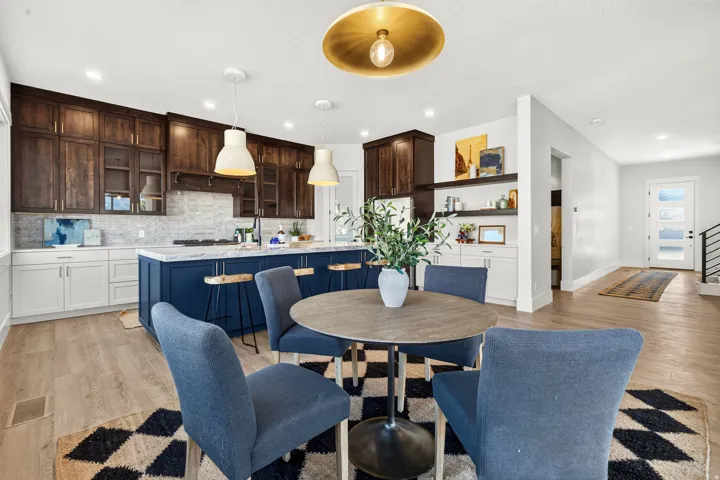 Open-concept living space featuring a gourmet kitchen with two-tone cabinetry, a large center island with seating, pendant lighting, and a backsplash