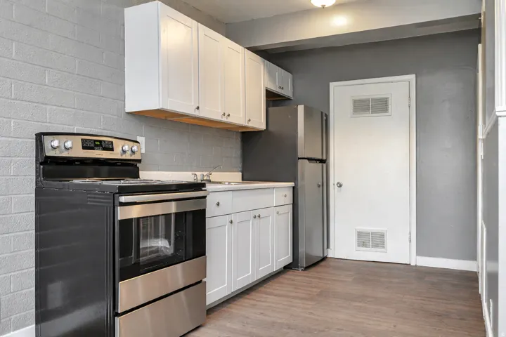 Kitchen featuring stainless steel appliances, white cabinets, light countertops, light wood-style floors, and decorative backsplash