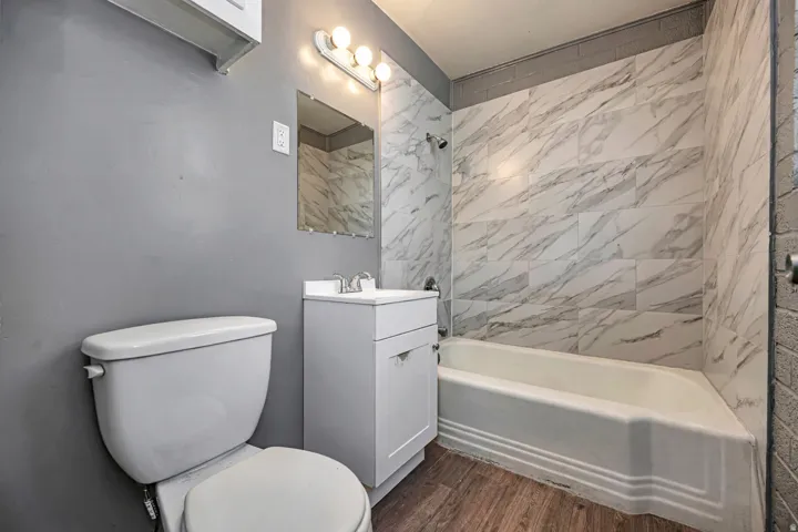 Full bath featuring vanity, dark wood-style floors, and shower / tub combination