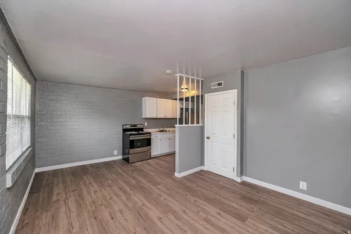 Kitchen featuring stainless steel electric range oven, light countertops, white cabinetry, and dark wood-style flooring