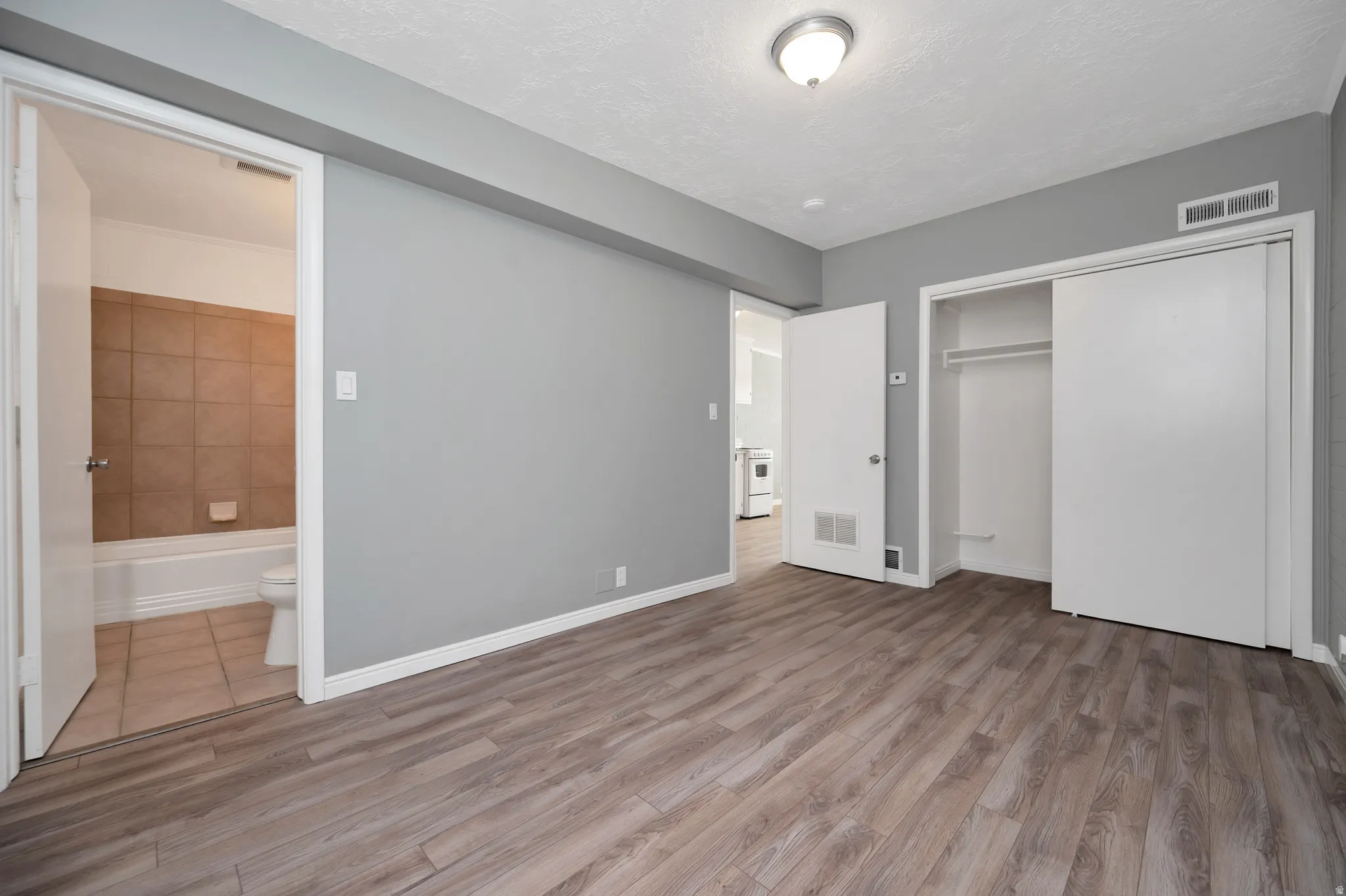 Unfurnished bedroom with a closet, light wood-type flooring, and connected bathroom