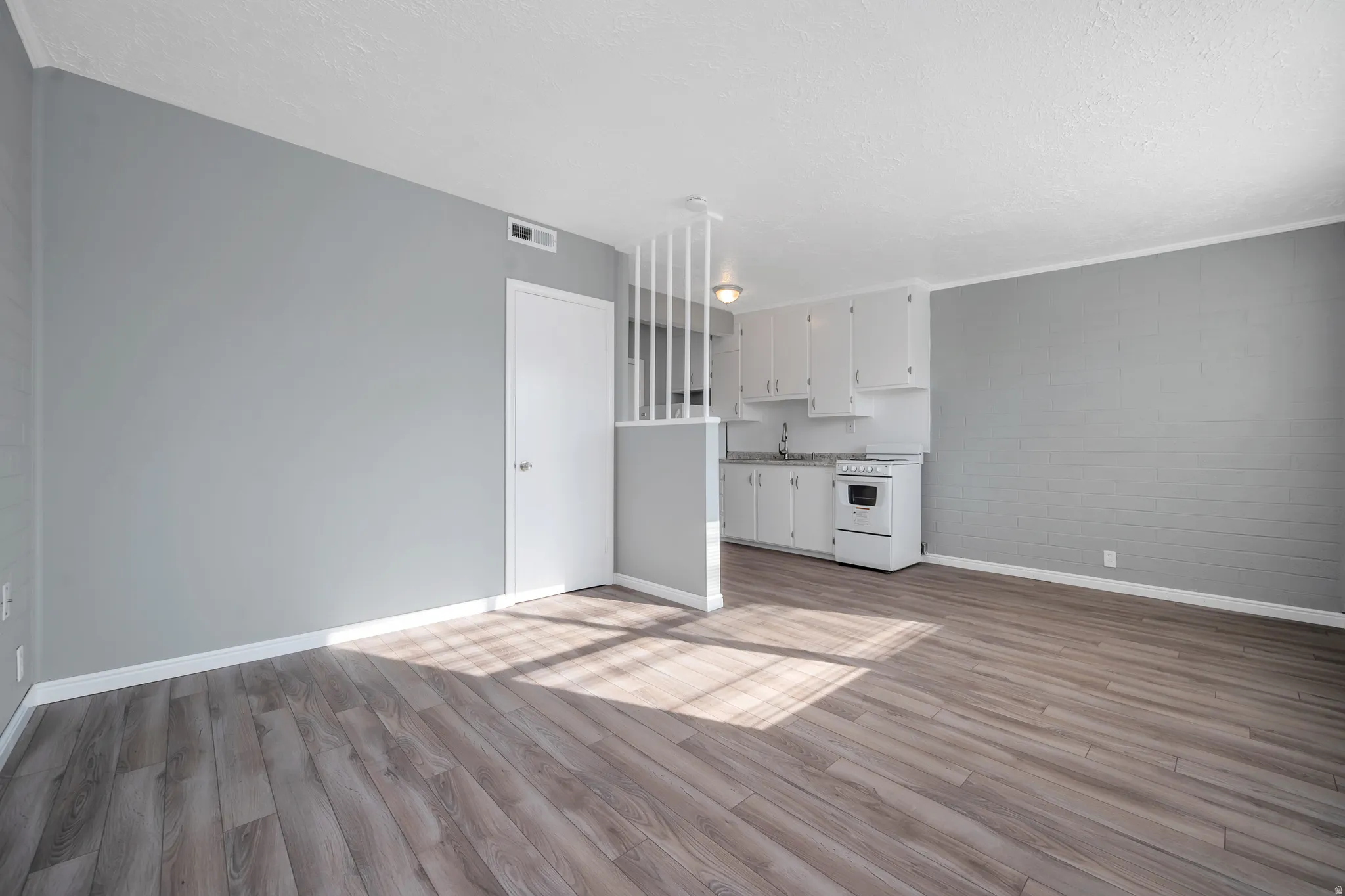 Unfurnished living room featuring concrete block wall, light wood-style floors, and a textured ceiling