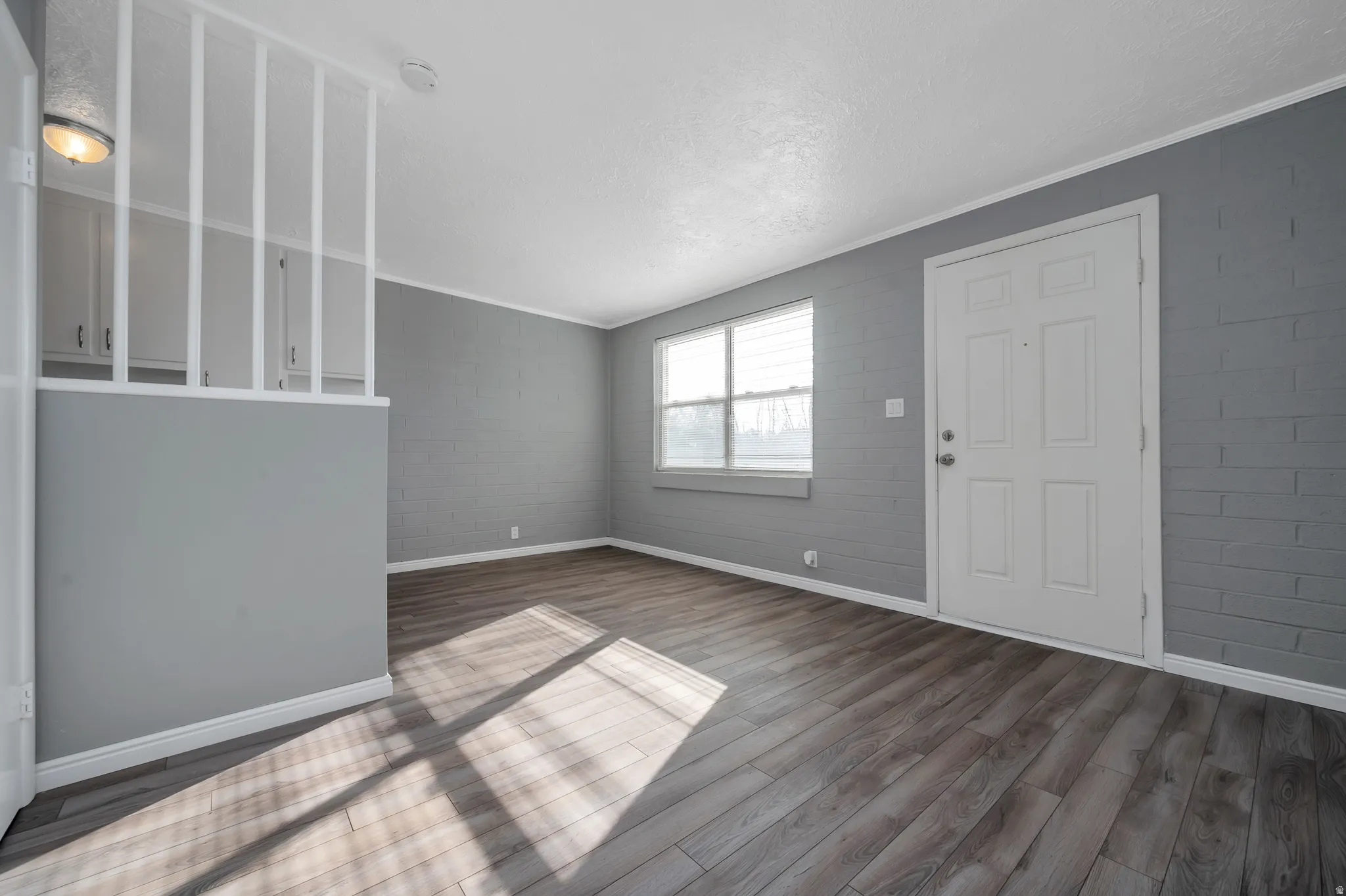 Entrance foyer featuring dark wood-type flooring, ornamental molding, concrete block wall, and a textured ceiling