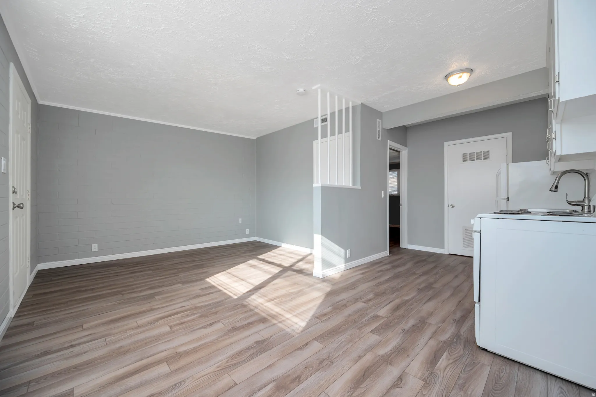 Unfurnished living room with light wood finished floors and a textured ceiling