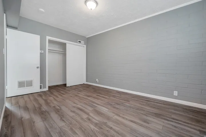 Unfurnished bedroom with a closet, wood finished floors, a textured ceiling, and concrete block wall