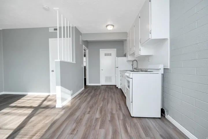 Kitchen featuring white stove, light countertops, white cabinetry, light wood finished floors, and a textured ceiling