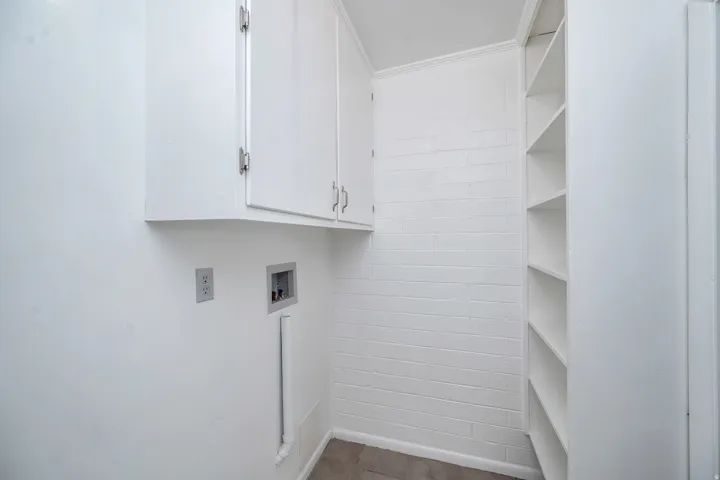 Laundry area featuring hookup for a washing machine, cabinet space, and ornamental molding