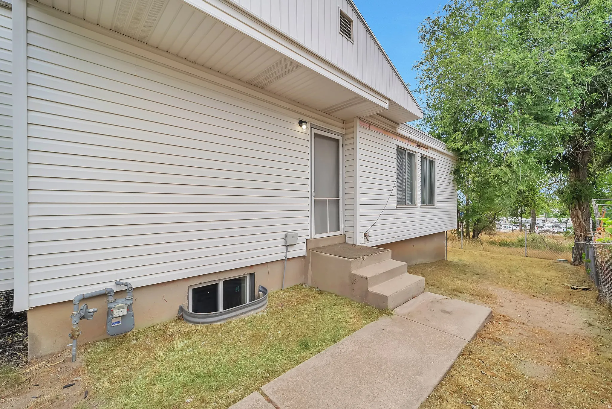 White siding exterior with concrete steps and a screen door entry