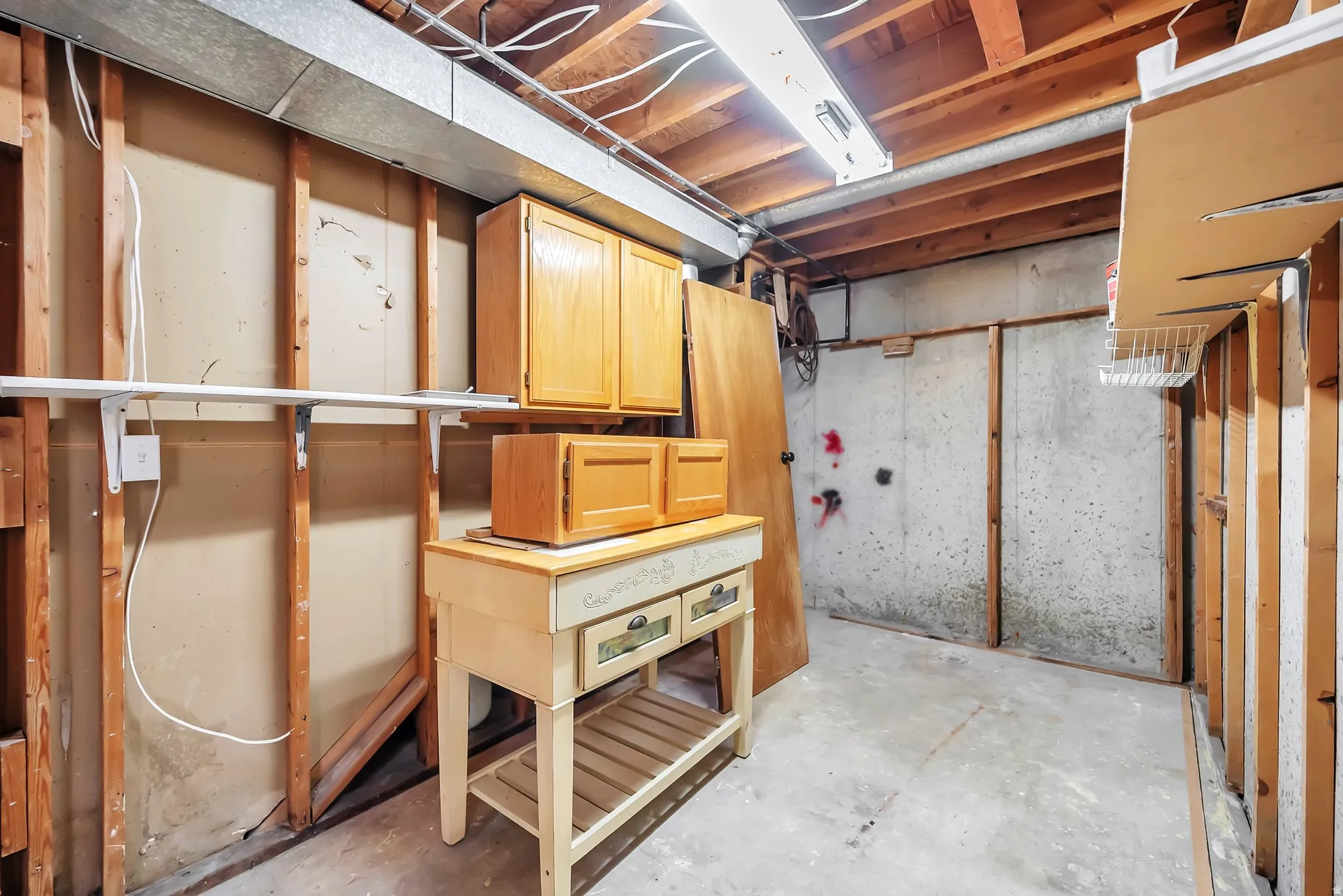 Basement area featuring exposed concrete walls and wood framing