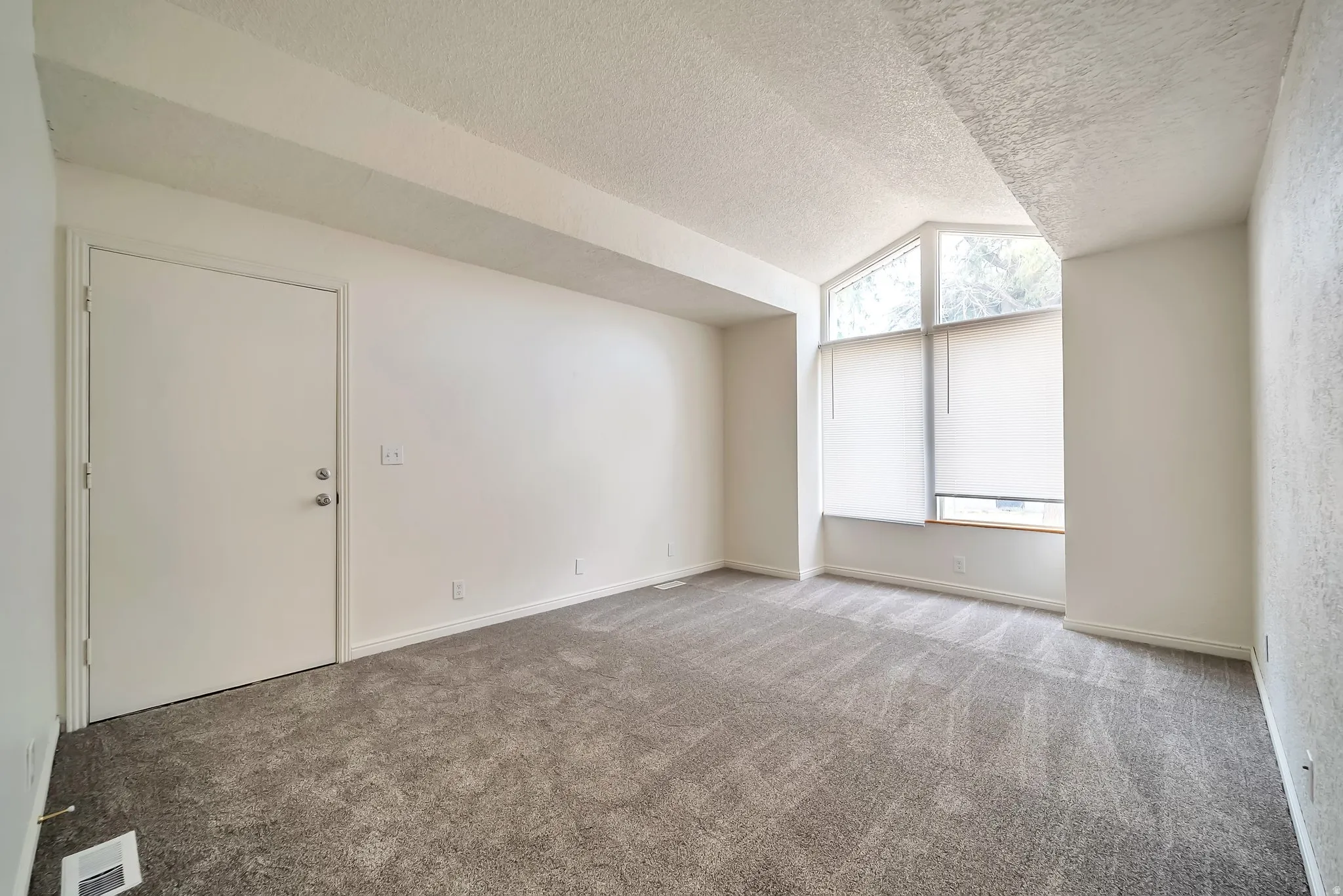 Room featuring grey patterned carpeting, white walls, and a textured ceiling