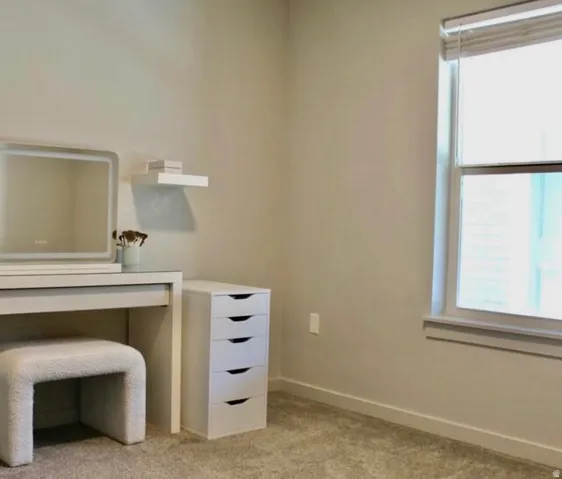 Carpeted room with a window featuring blinds and a white sill