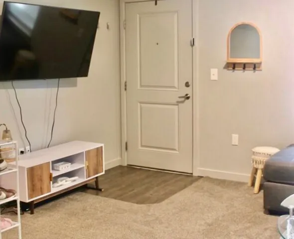 Entryway featuring a paneled door, wood-finish flooring, and light-toned carpeting