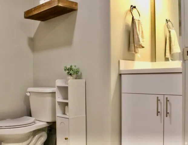 White vanity with a solid surface countertop, undermount sink, and contemporary hardware