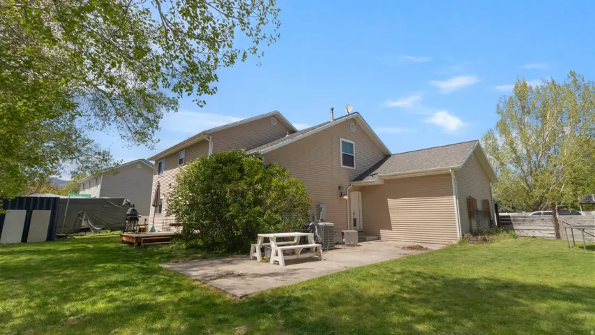 Expansive rear yard featuring a concrete patio, wood deck, and lhttps://assets.utahrealestate.com/photos/280x210/2156986_c82bd7bf6cffa3650365e17b692d2b5f_6a70b0bf54e75.jpgush green lawn