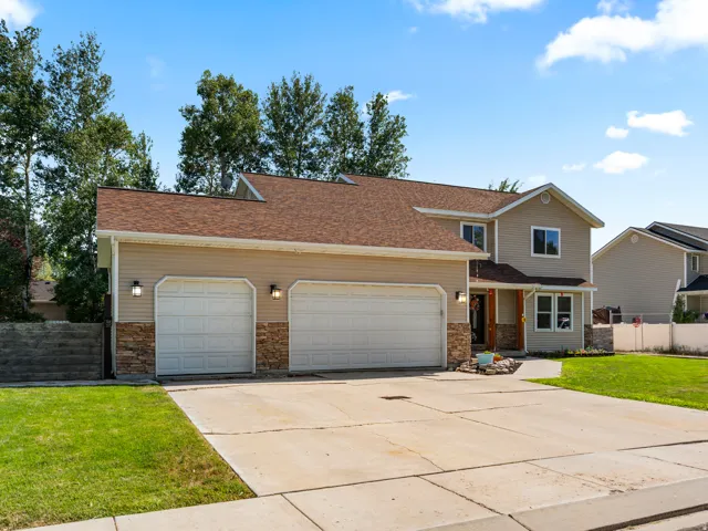 Two-story property featuring tan horizontal siding and a brown shingle roof