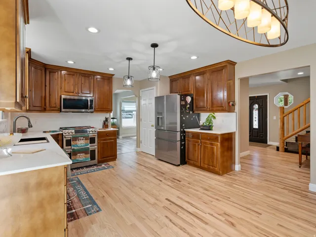 Spacious kitchen featuring light wood-finish flooring, extensive wood cabinetry, and stainless steel appliances