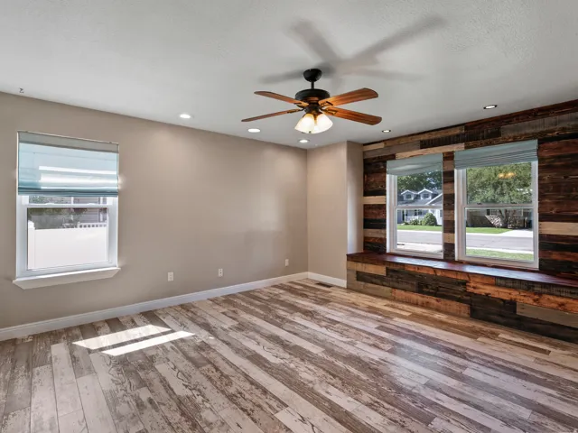 Living area featuring wood-finish flooring, a decorative wood accent wall with integrated window seating, and recessed lighting