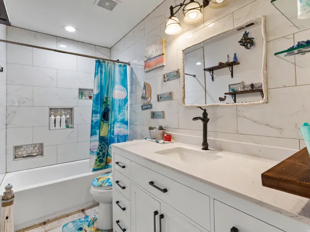 Bathroom featuring a white vanity with panel cabinetry and black hardware, a rectangular undermount sink, and a countertop