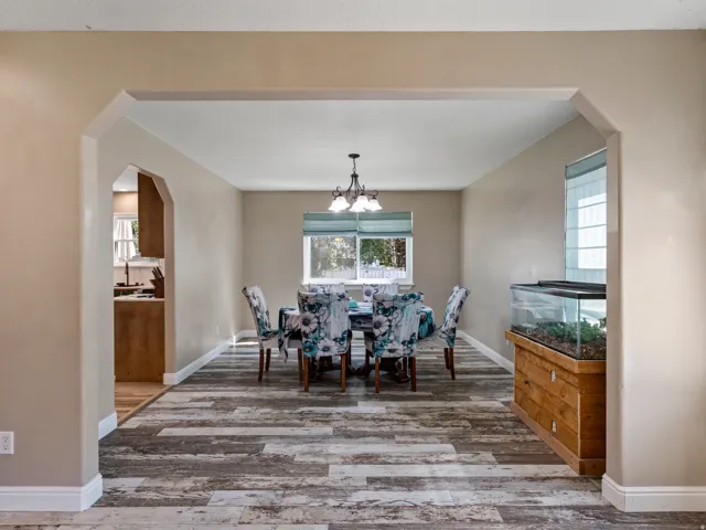 Spacious dining area featuring wood-finish flooring, neutral wall tones, and arched entryways