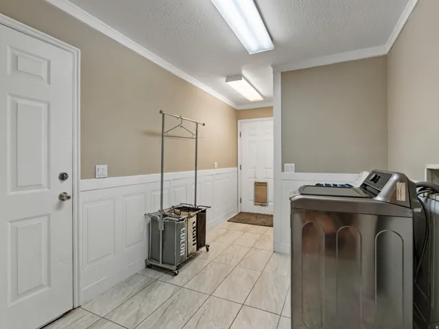 Utility room featuring paneled wainscoting, neutral wall paint, tile flooring, and overhead fluorescent lighting