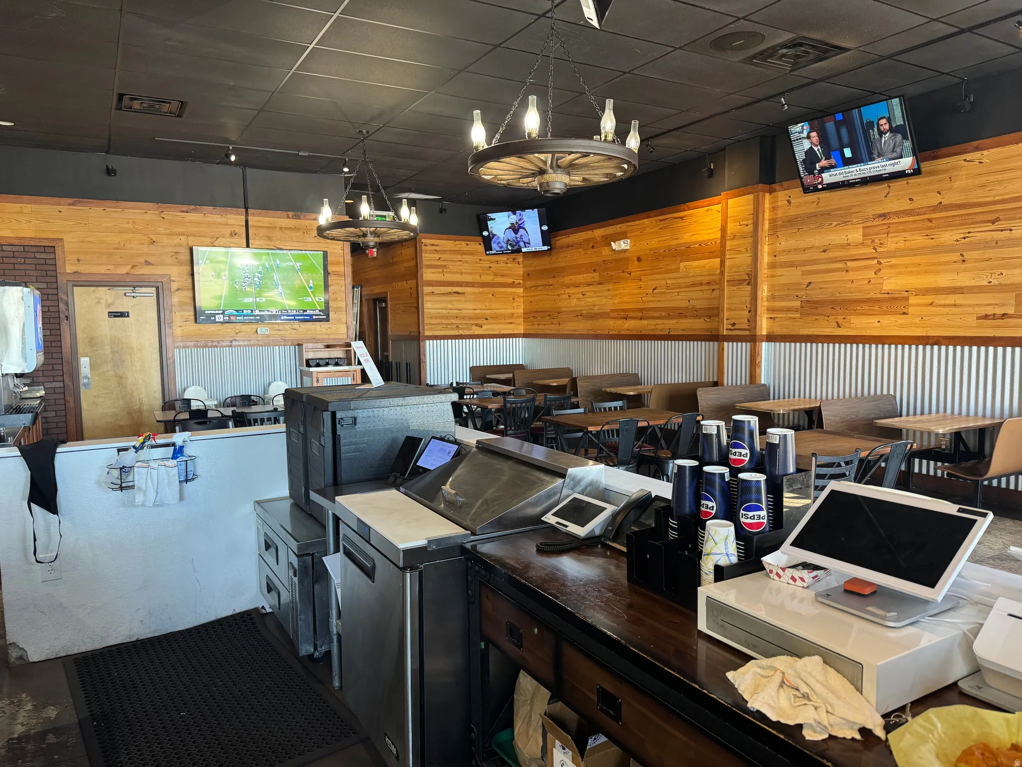 Commercial interior featuring wood-panel walls, corrugated metal wainscoting, and a dark ceiling