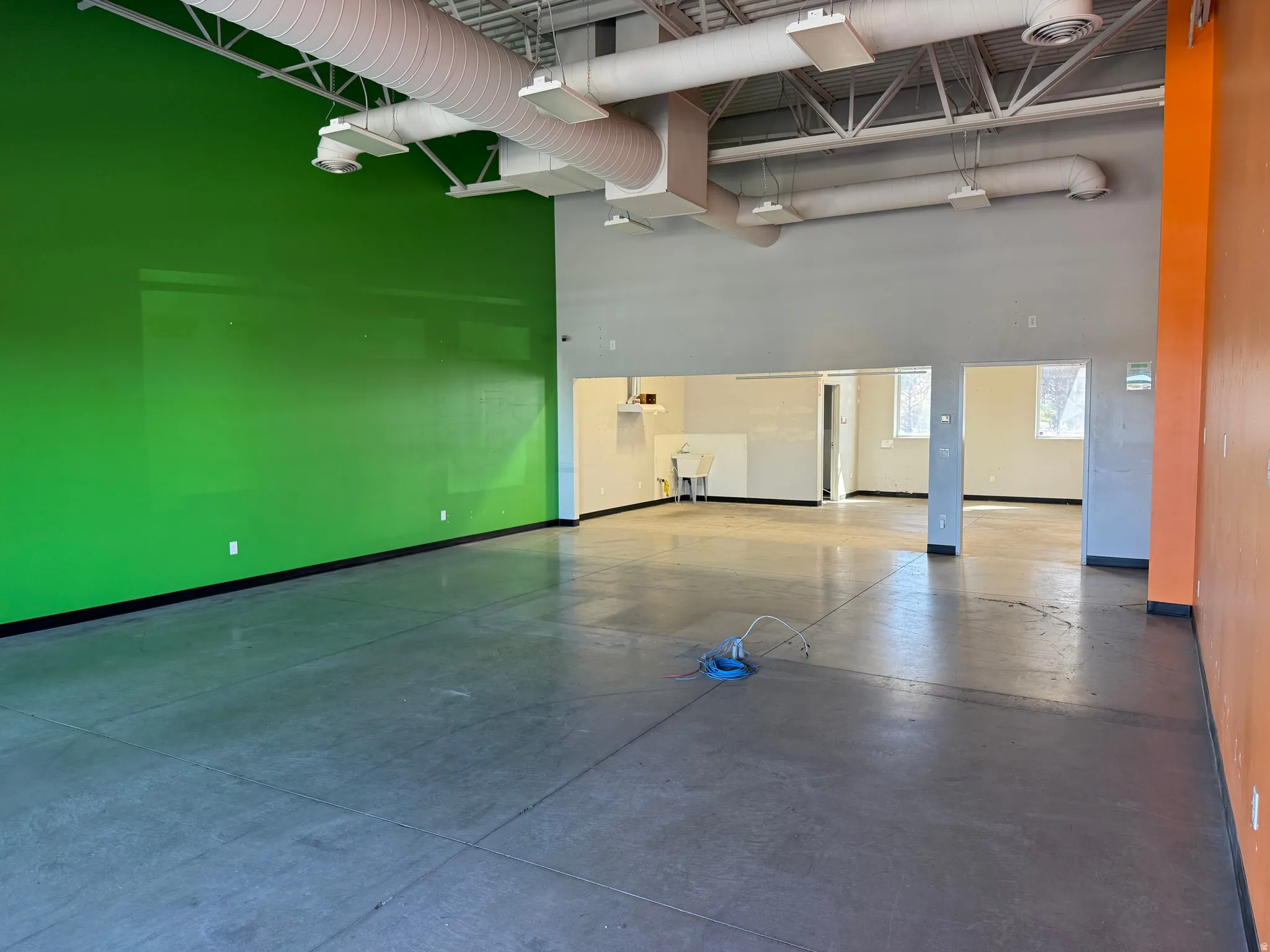 Spacious open-concept interior featuring concrete flooring, exposed ceiling ductwork, and track lighting
