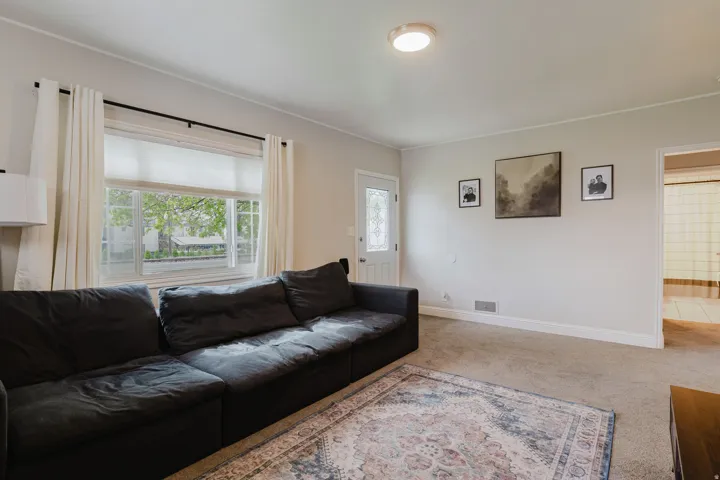 Living area featuring light neutral wall paint, carpet flooring, baseboard trim, and a ceiling-mounted light fixture