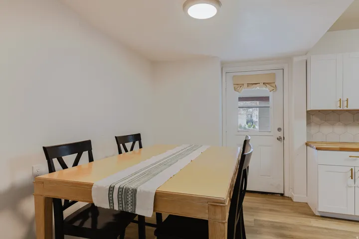 Dining area featuring wood-finish flooring, white walls, and a contemporary flush-mount ceiling light