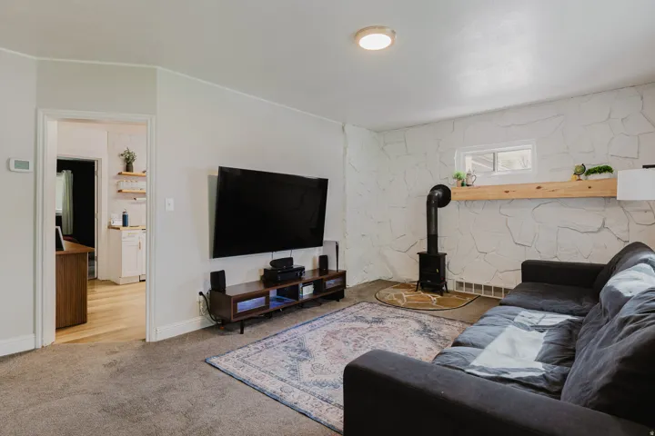 Living area featuring a stone accent wall, wood-finish flooring, and a freestanding stove