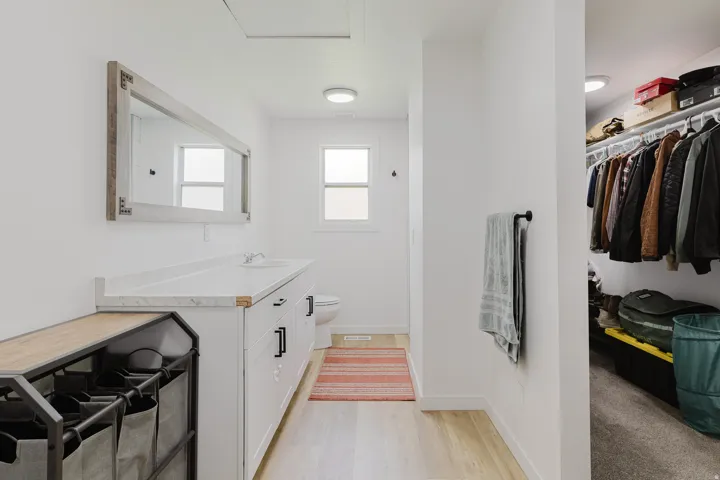Bathroom featuring a single vanity with a white countertop, undermount sink, and black cabinet hardware