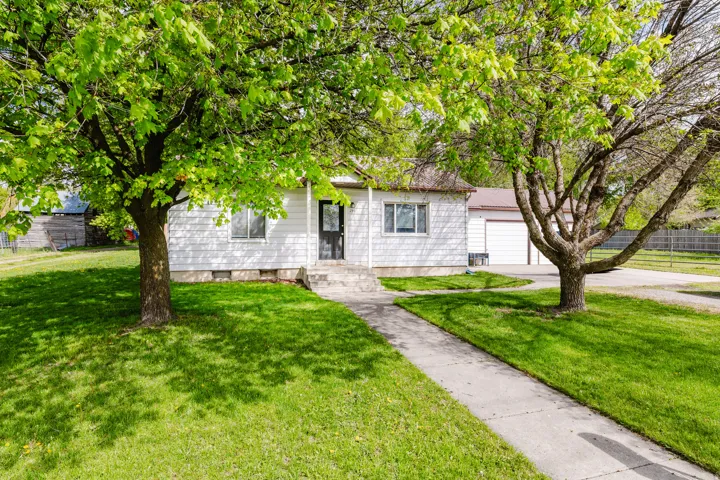 Ranch-style residence featuring white siding, a dark entry door, and a concrete pathway