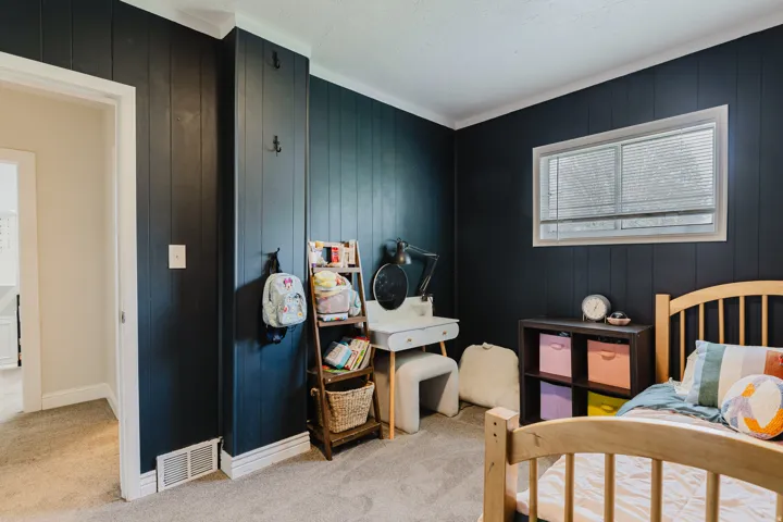 Room featuring dark paneled walls with white trim and a window with blinds