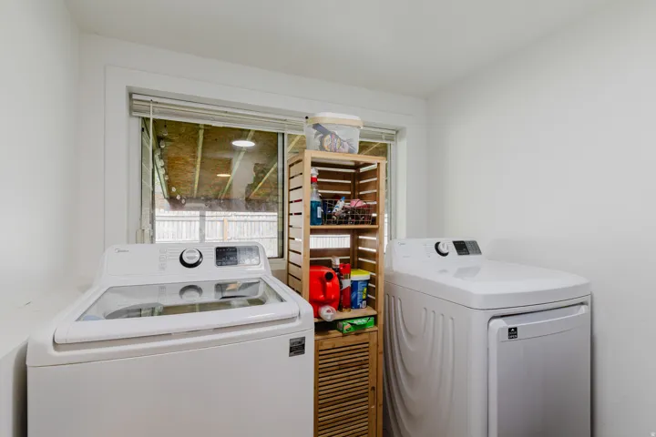 Dedicated laundry area with a large window, white walls, and bright overhead lighting