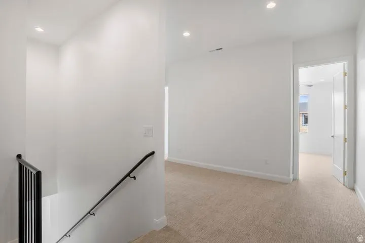 Upper-level landing featuring neutral carpeting and recessed lighting