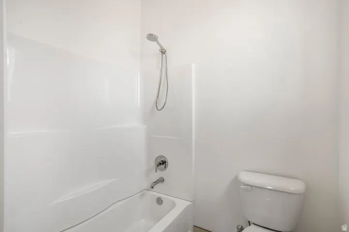 Bathtub and shower combination featuring a white surround, chrome fixtures, and a handheld showerhead