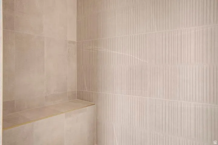 Neutral-toned tile shower featuring a built-in bench