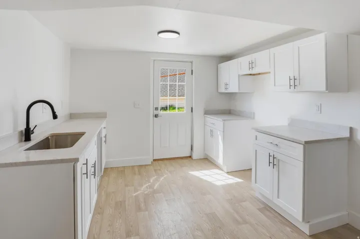 Bright kitchen space featuring white shaker-style cabinetry, light wood-finish flooring, and light-toned countertops