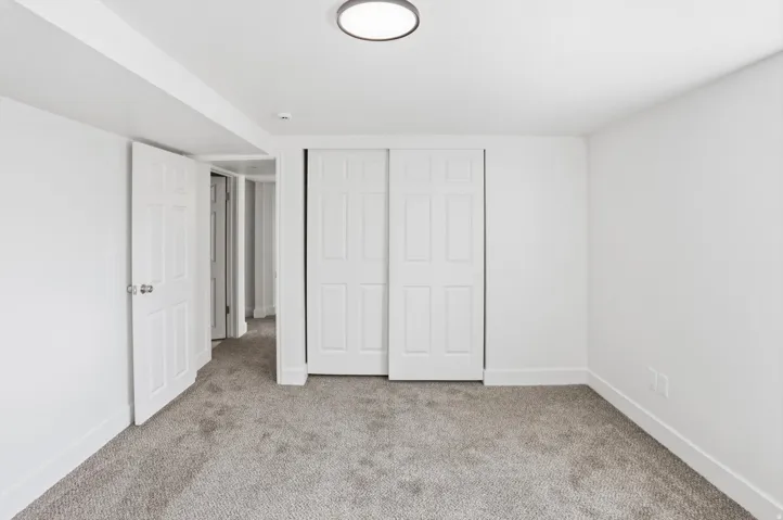 Neutral tone carpeting, white walls, and bright overhead lighting