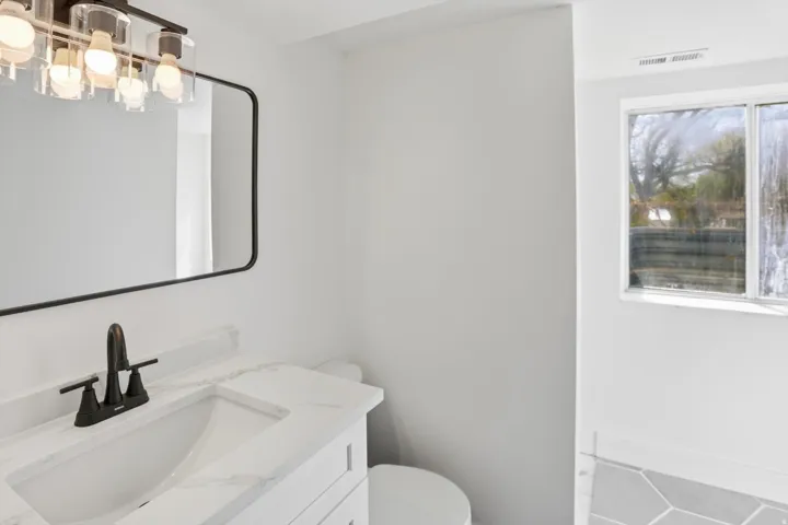 Bathroom featuring a white vanity with integrated sink, white countertop, and dark-finished faucet
