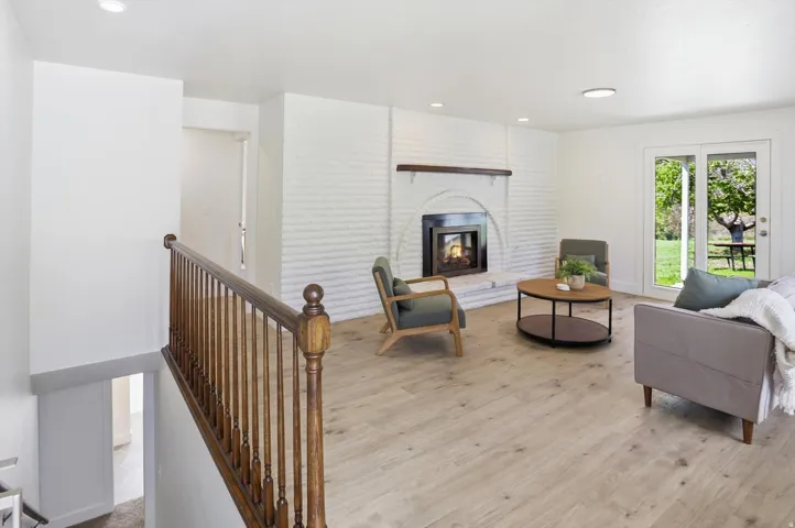 Living area featuring wood-finish flooring and a white brick fireplace with a wood mantle
