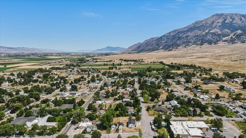 Expansive aerial perspective showcasing a community nestled against a large mountain range and surrounded by agricultural fields