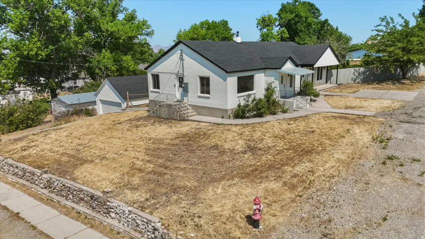 White exterior residence featuring a dark shingle roof, attached garage, and paved driveway