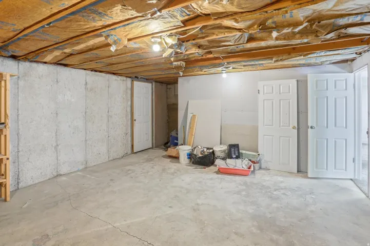 Unfinished basement with concrete slab flooring and exposed ceiling joists