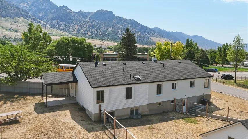 White siding exterior with a dark shingle roof, featuring multiple windows and a covered patio area
