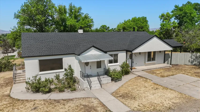 Ranch-style residence featuring a dark shingle roof and light-toned brick and siding exterior